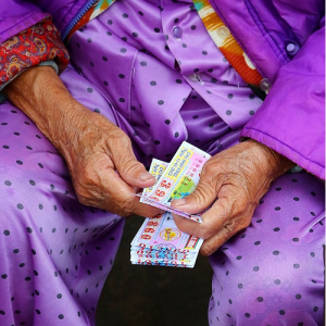 Une vieille femme qui vend des tickets de loto sur le trottoir à Hue